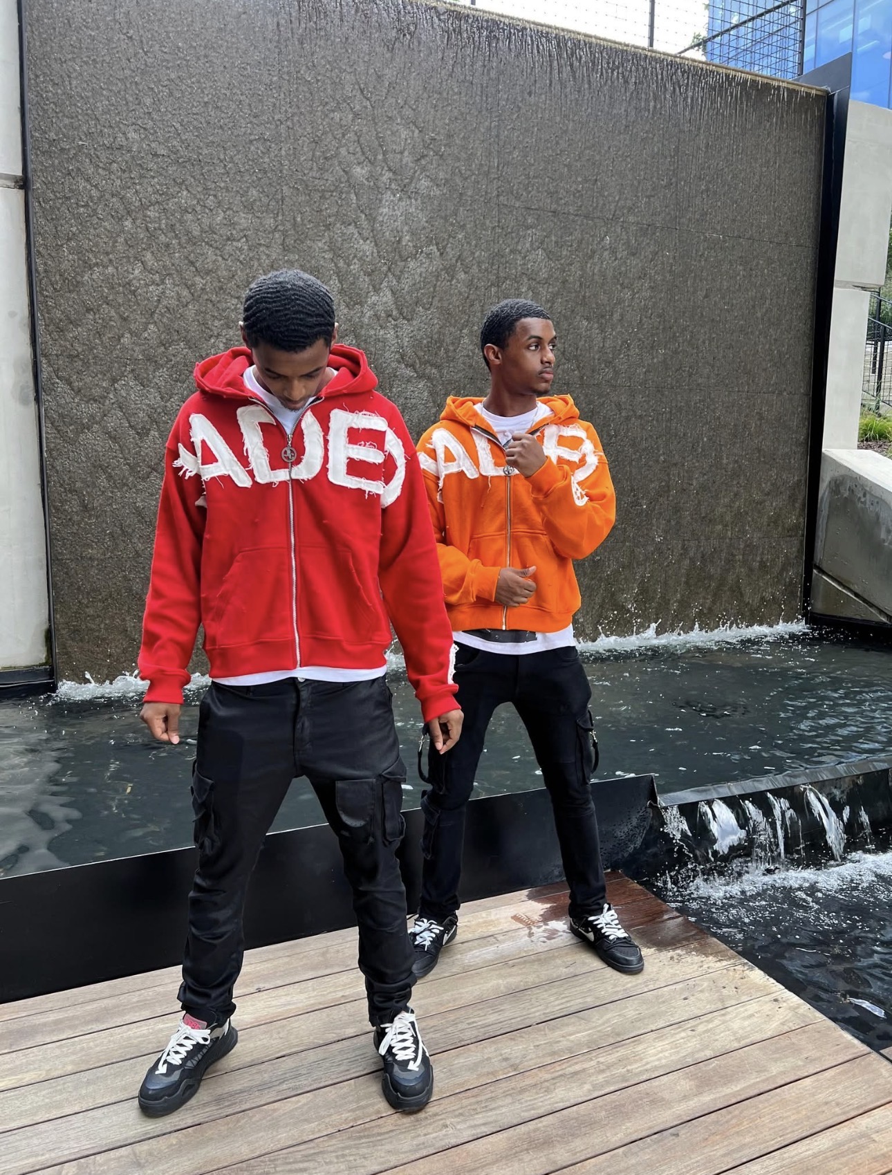 80k Twins standing together in ADE hoodies by a waterfall